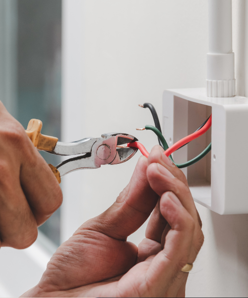 A pair of hands holding a pair of pliers and wires