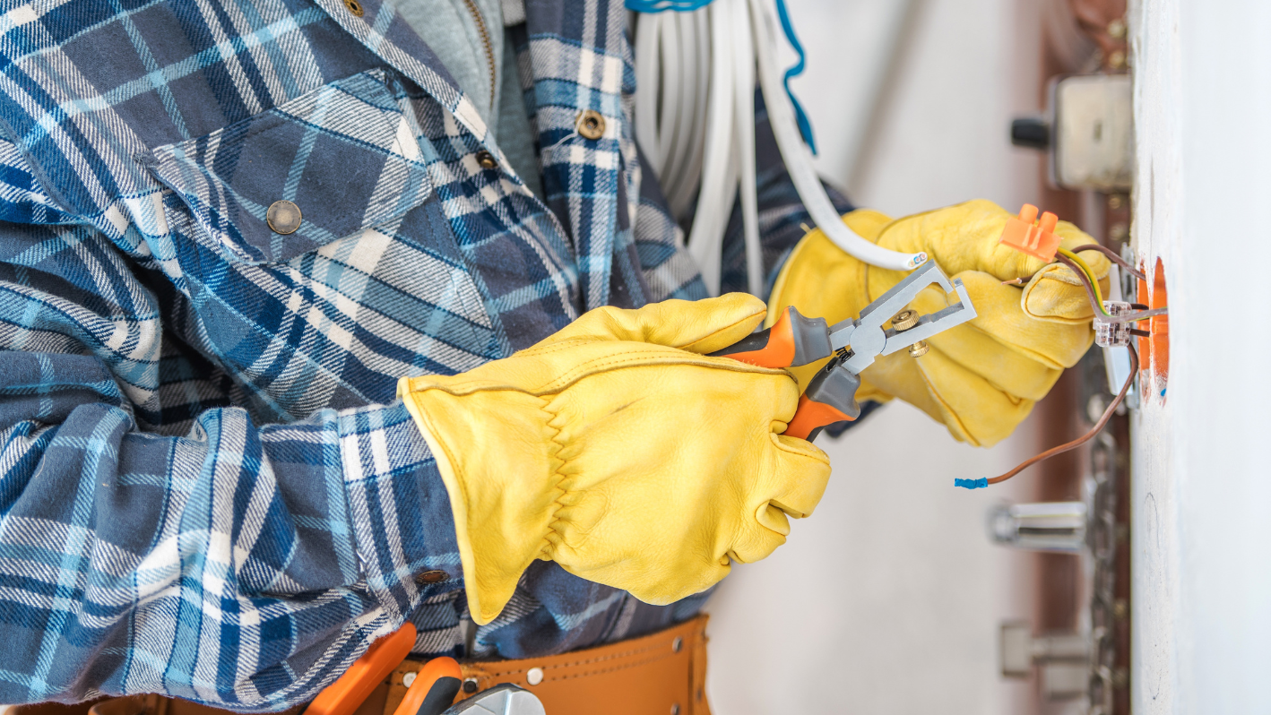 A person wearing yellow gloves and holding a pair of pliers