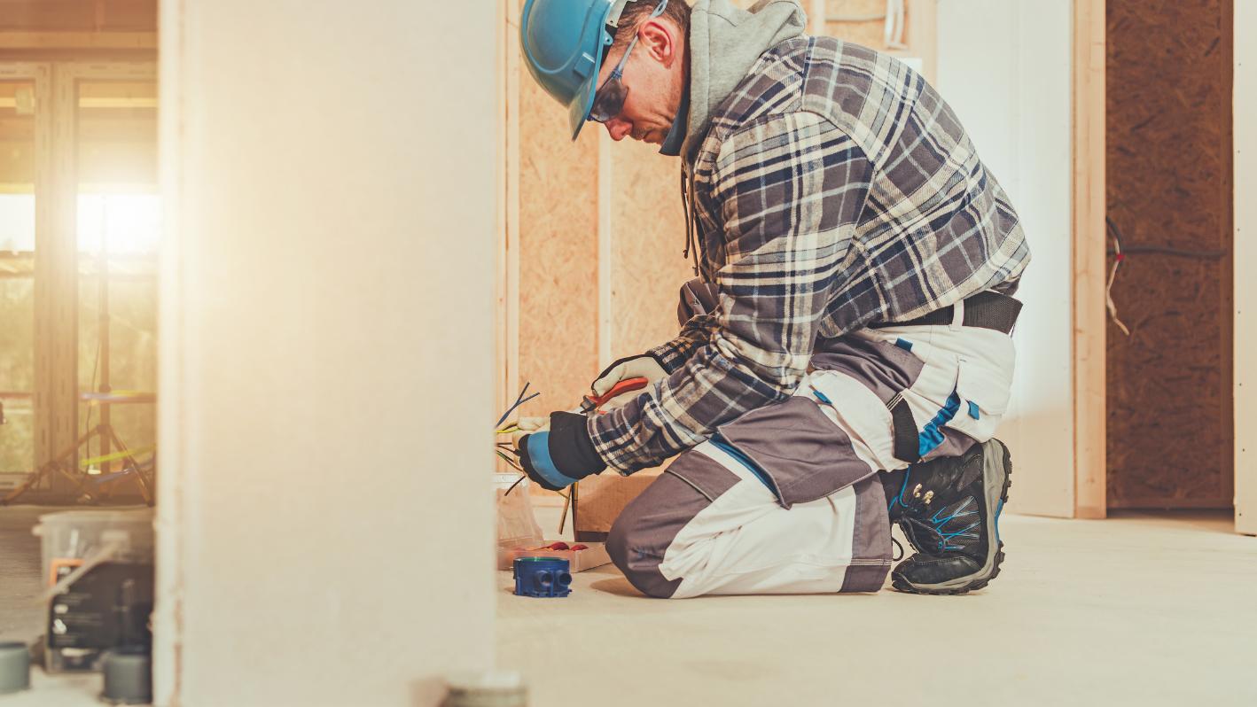 A man sitting on the floor working on a wall