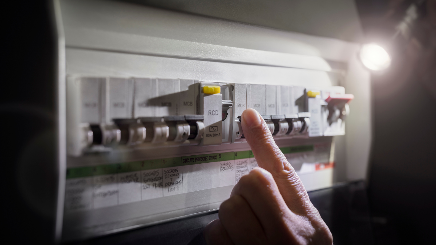 A person pointing at a light switch on a wall